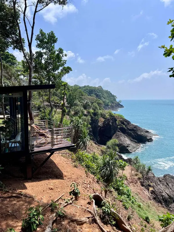 Terrasse en bois surplombant une côte rocheuse et la mer.