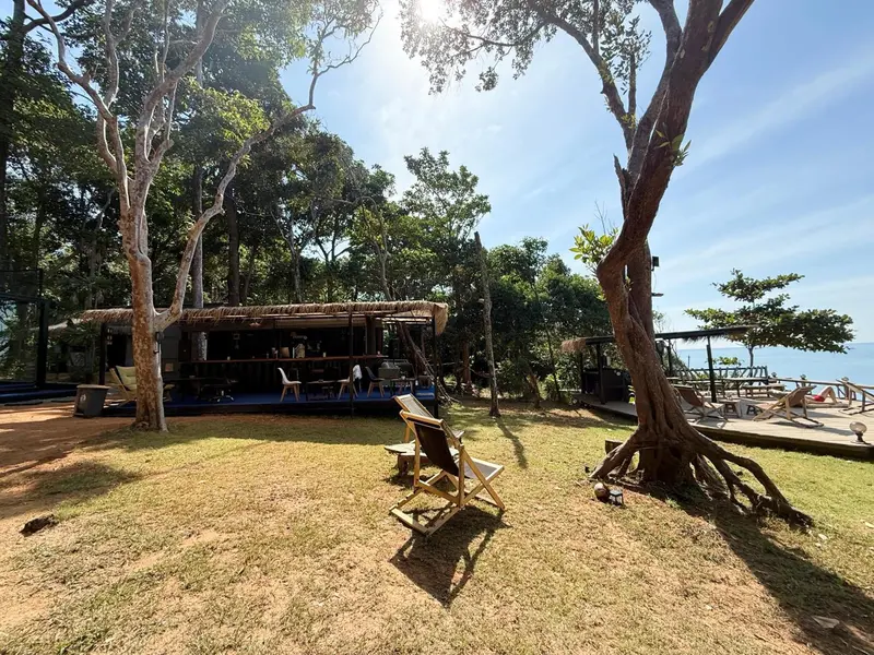 Terrasse ombragée avec chaises longues et vue sur la mer.