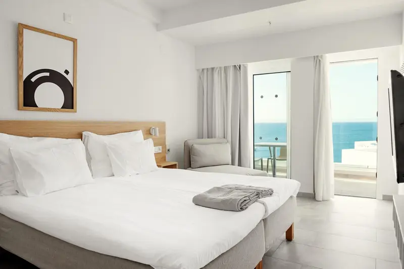 Une chambre lumineuse avec un grand lit et une vue sur la mer.