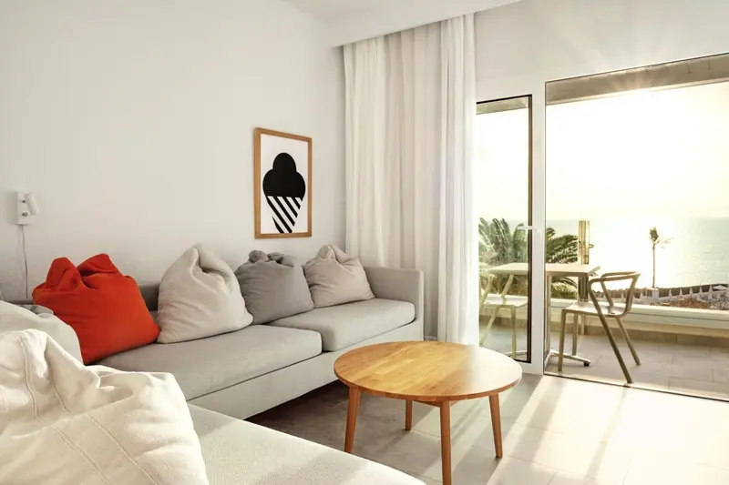 Un salon clair avec un canapé d'angle et une vue sur la mer.