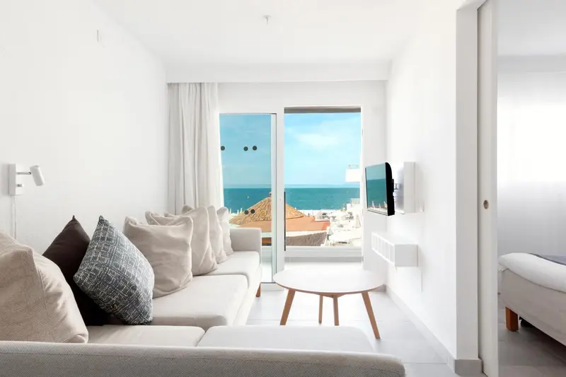 Espace de détente lumineux avec canapé et vue sur la mer.