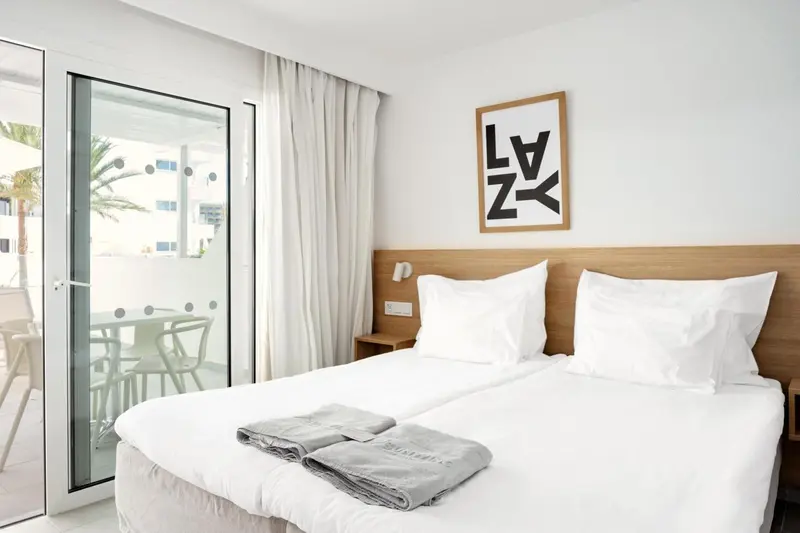 Une chambre lumineuse avec un grand lit et une vue sur une terrasse.