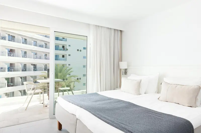 Une chambre lumineuse avec un grand lit et un accès à un balcon.