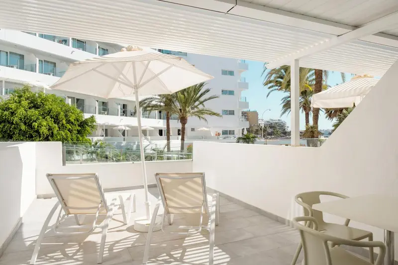 Deux transats blancs invitent à la détente sur une terrasse ensoleillée.
