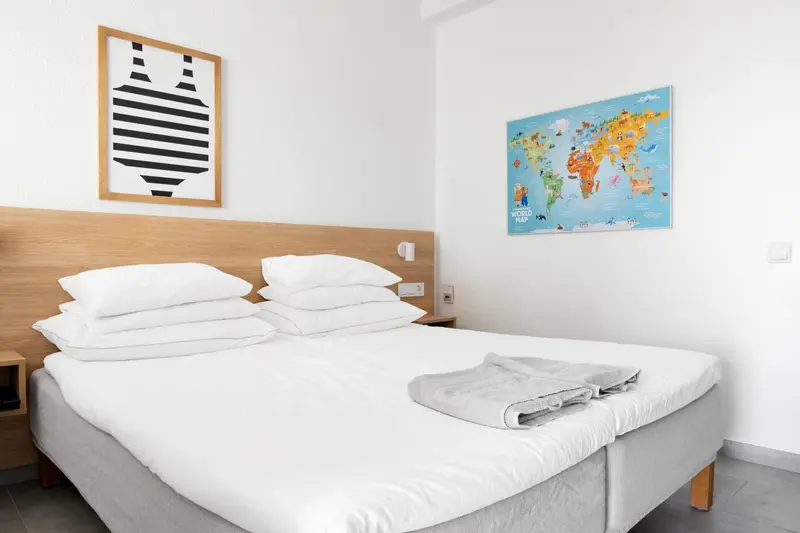 Une chambre lumineuse avec un grand lit recouvert de draps blancs.