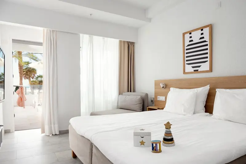 Chambre lumineuse avec un grand lit et un coin salon.