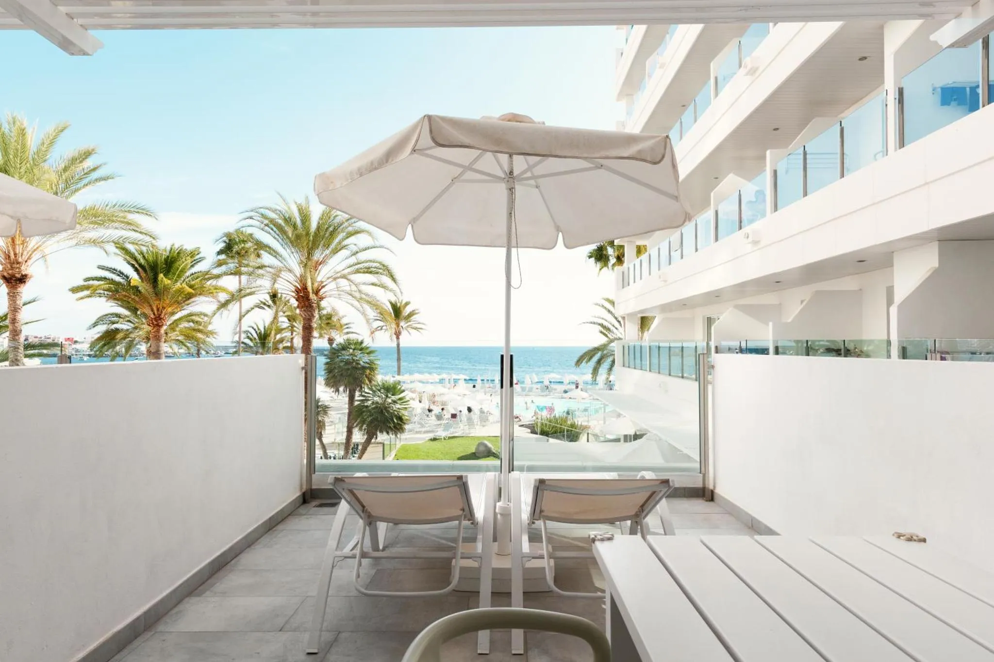 Deux transats blancs invitent à la détente sur une terrasse ensoleillée avec vue sur la mer.