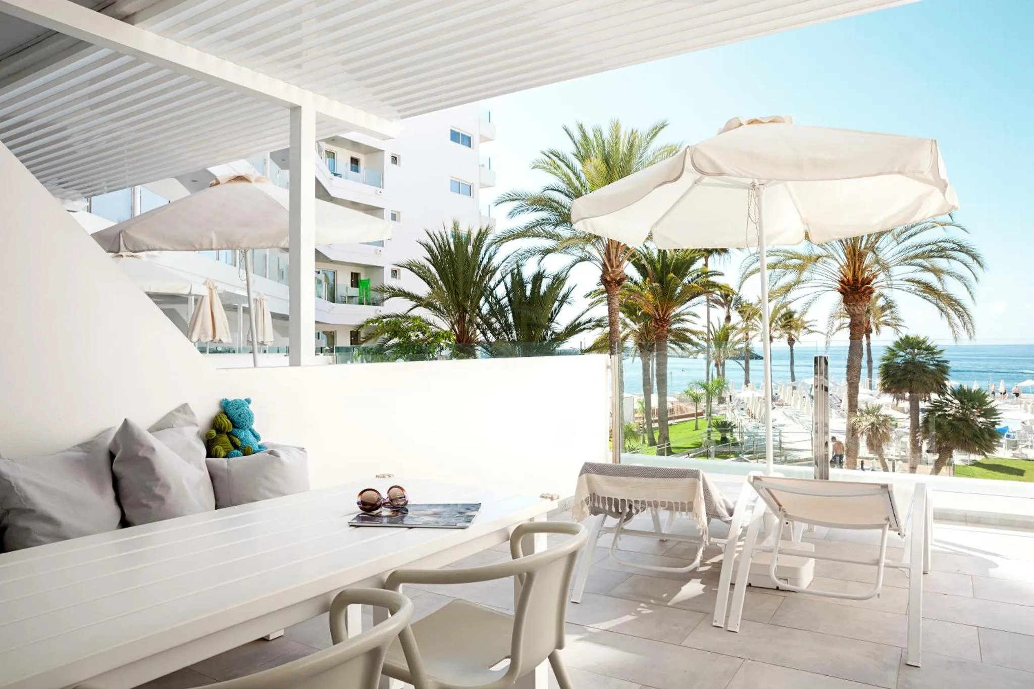 Terrasse aménagée avec table, chaises et transats face à la mer.