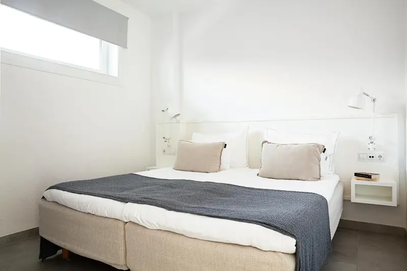 Une chambre lumineuse avec un grand lit et des tables de chevet murales.