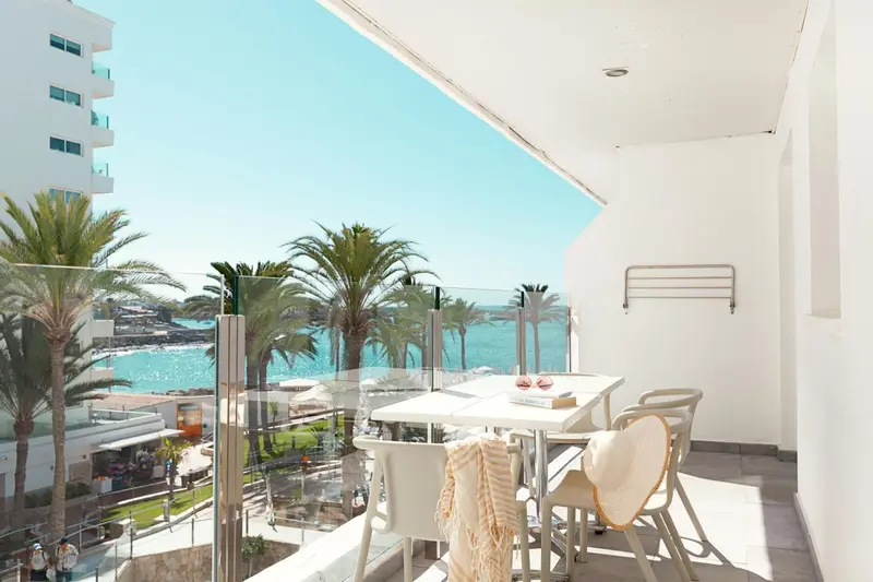 Une terrasse ensoleillée offre une vue dégagée sur la mer et la végétation.