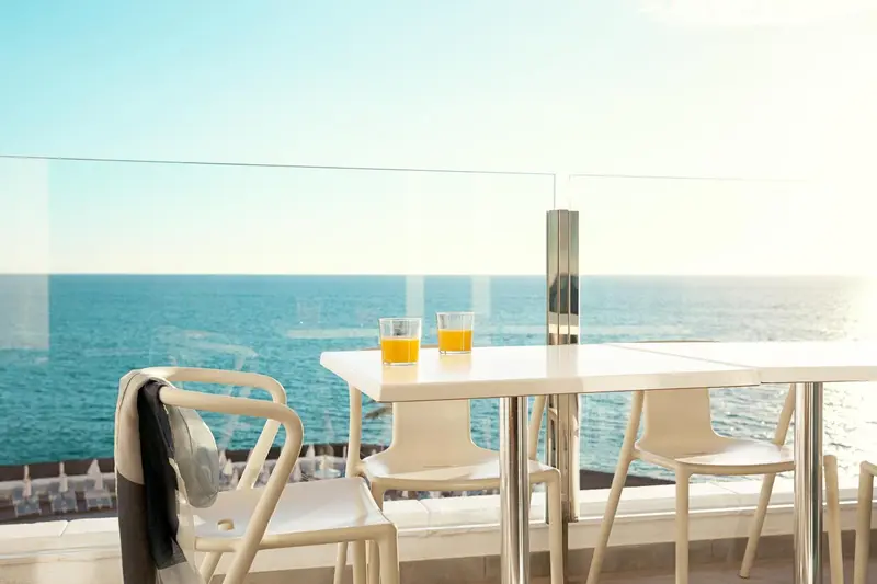 Terrasse avec table et chaises donnant sur la mer.