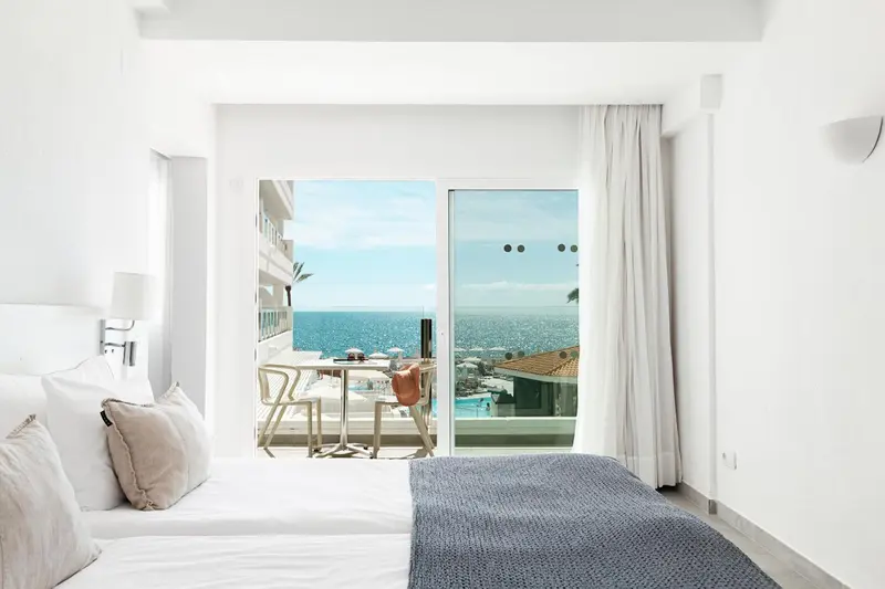 Une chambre lumineuse s'ouvre sur une terrasse avec vue sur la mer.
