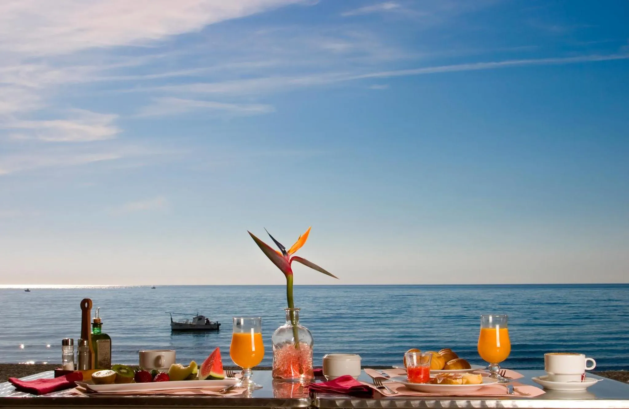 Une table est dressée avec des plats et des boissons face à la mer.