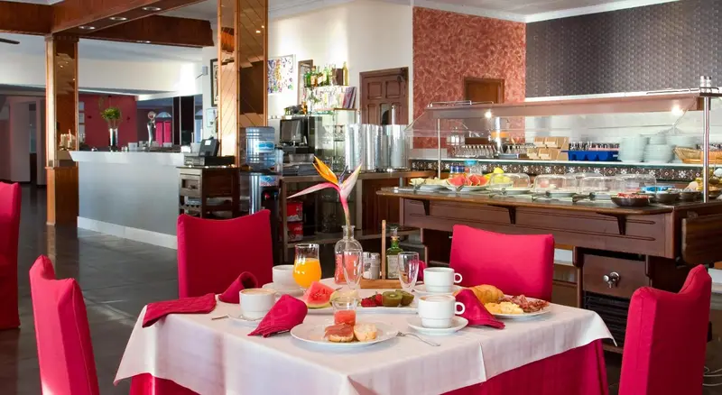 Une table est dressée pour le petit-déjeuner avec des viennoiseries et des fruits.