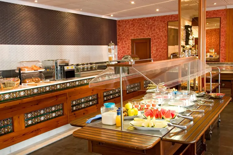Un buffet propose des pâtisseries, des fruits et des boissons dans une salle lumineuse.