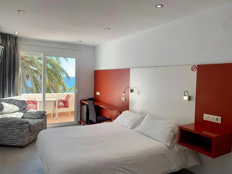 Une chambre lumineuse avec un grand lit et un accès à un balcon.