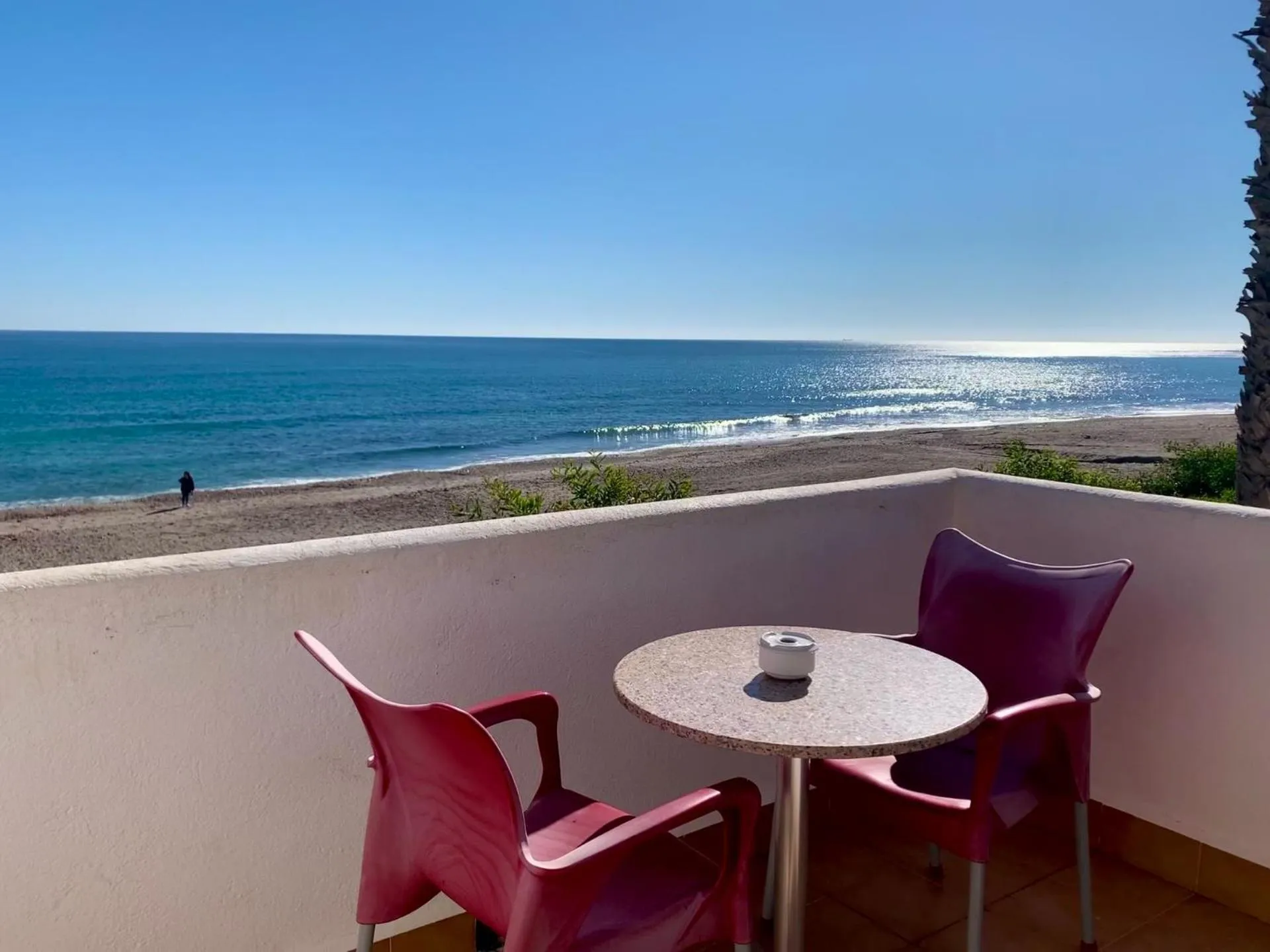 Terrasse avec table et chaises donnant sur la mer.
