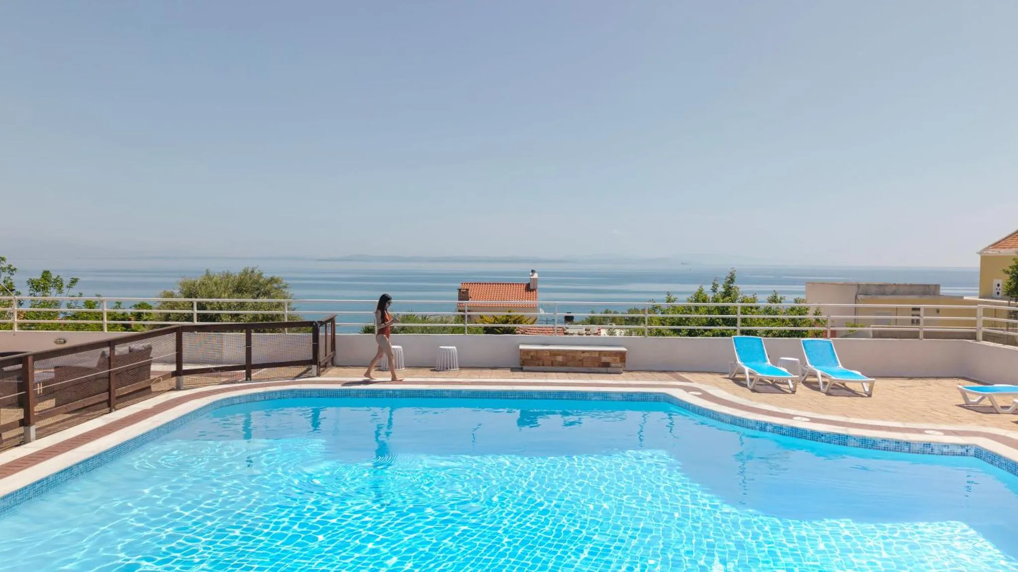 Une piscine bleue avec des transats et une vue sur la mer.
