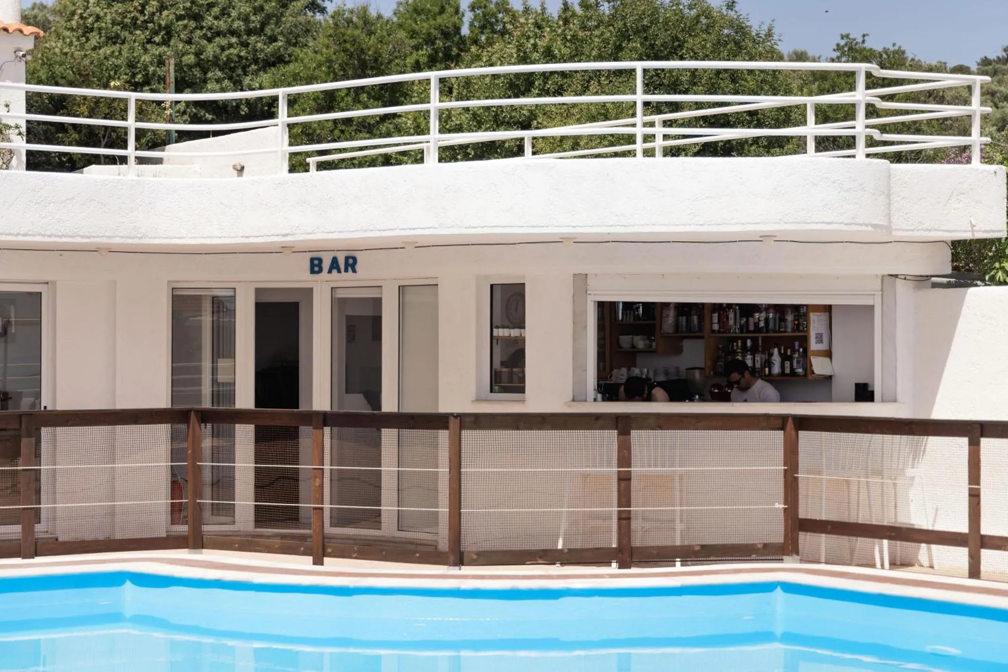 Un bar en plein air surplombe une piscine bleue.