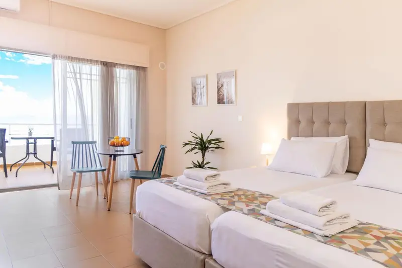 Une chambre lumineuse avec un grand lit et un coin repas donnant sur une terrasse.