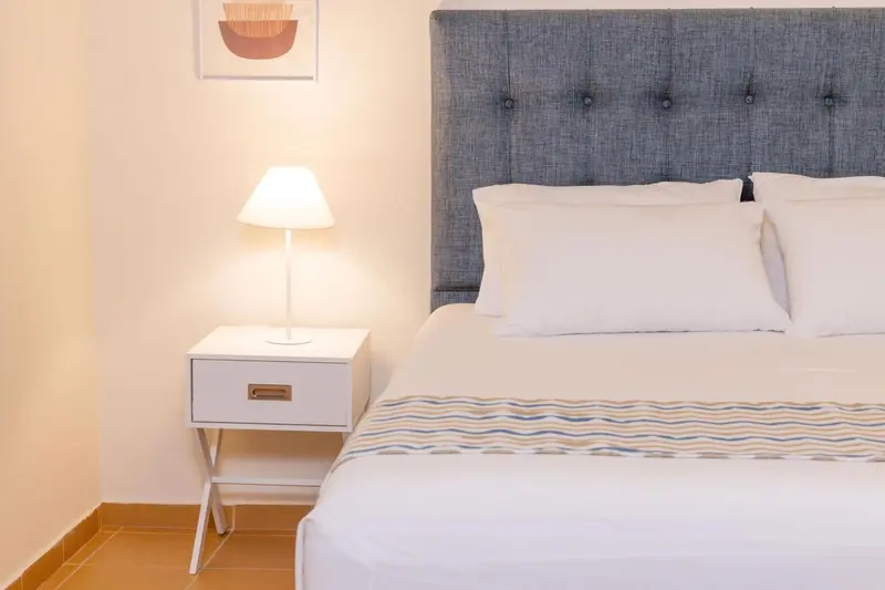 Une chambre lumineuse avec un grand lit recouvert d'une courtepointe.