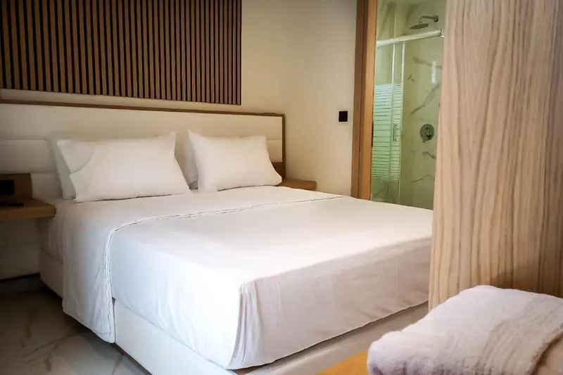 Une chambre lumineuse avec un grand lit et une salle de bain attenante.