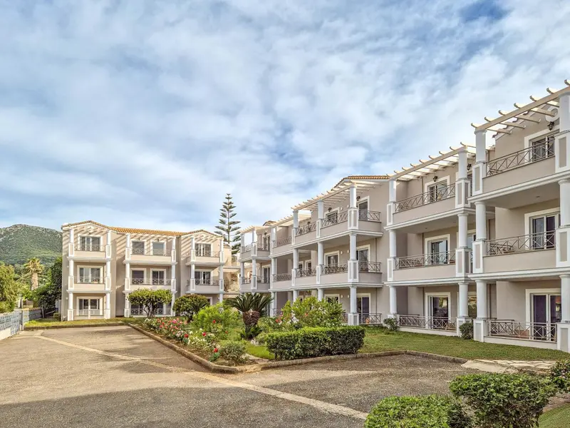 Bâtiment blanc à colonnes avec des balcons et une végétation luxuriante.