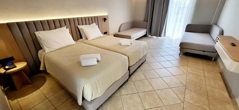 Chambre moderne avec deux lits simples et un coin salon.