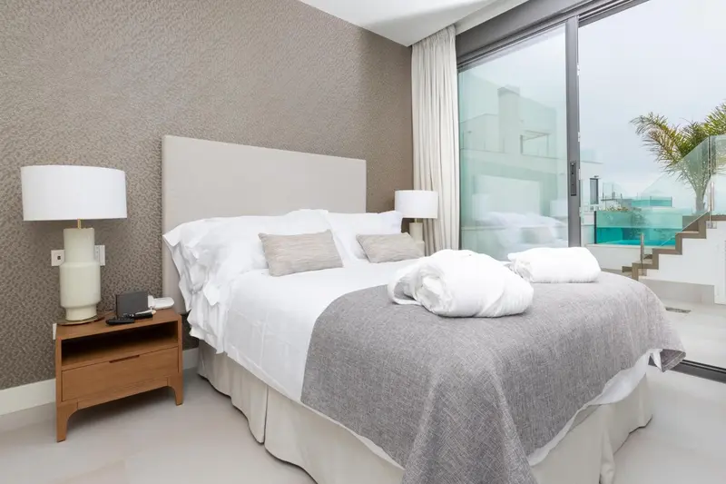 Une chambre lumineuse avec un grand lit et une vue sur l'extérieur.