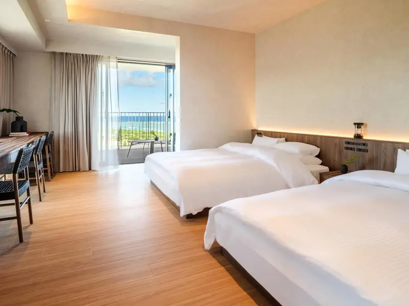 Une chambre lumineuse avec deux lits et une vue sur la mer.