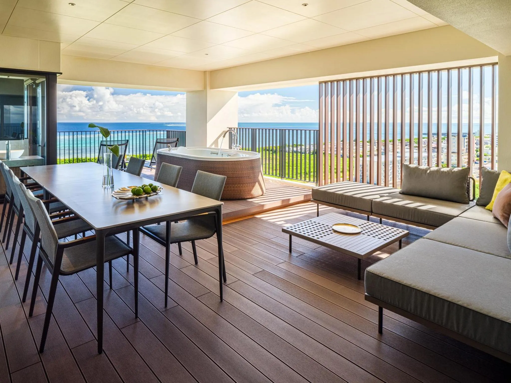 Une grande terrasse aménagée avec un coin repas et un espace détente face à la mer.