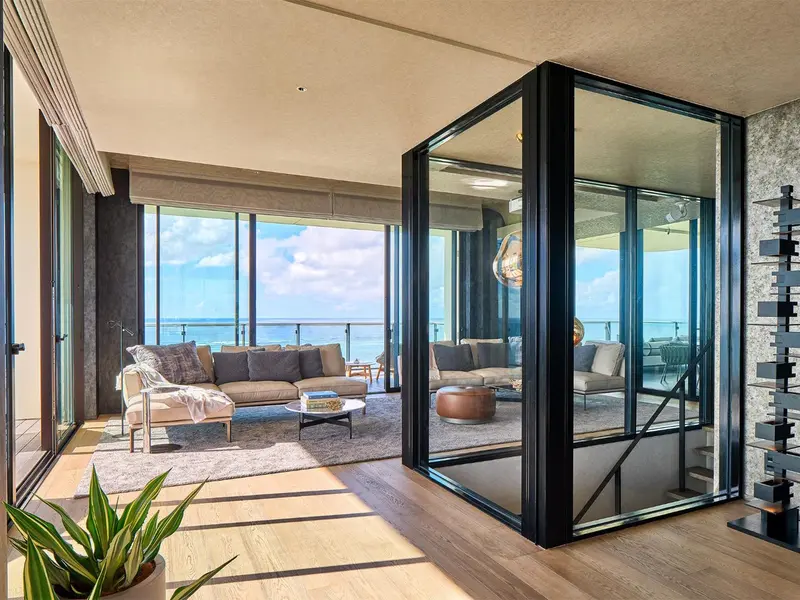 Espace de vie moderne avec canapés et vue sur l'océan à travers de grandes baies vitrées.