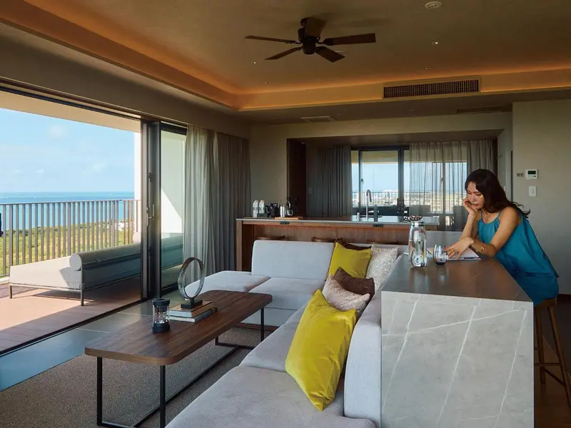 Espace de vie lumineux avec canapé, table basse et vue sur la mer.