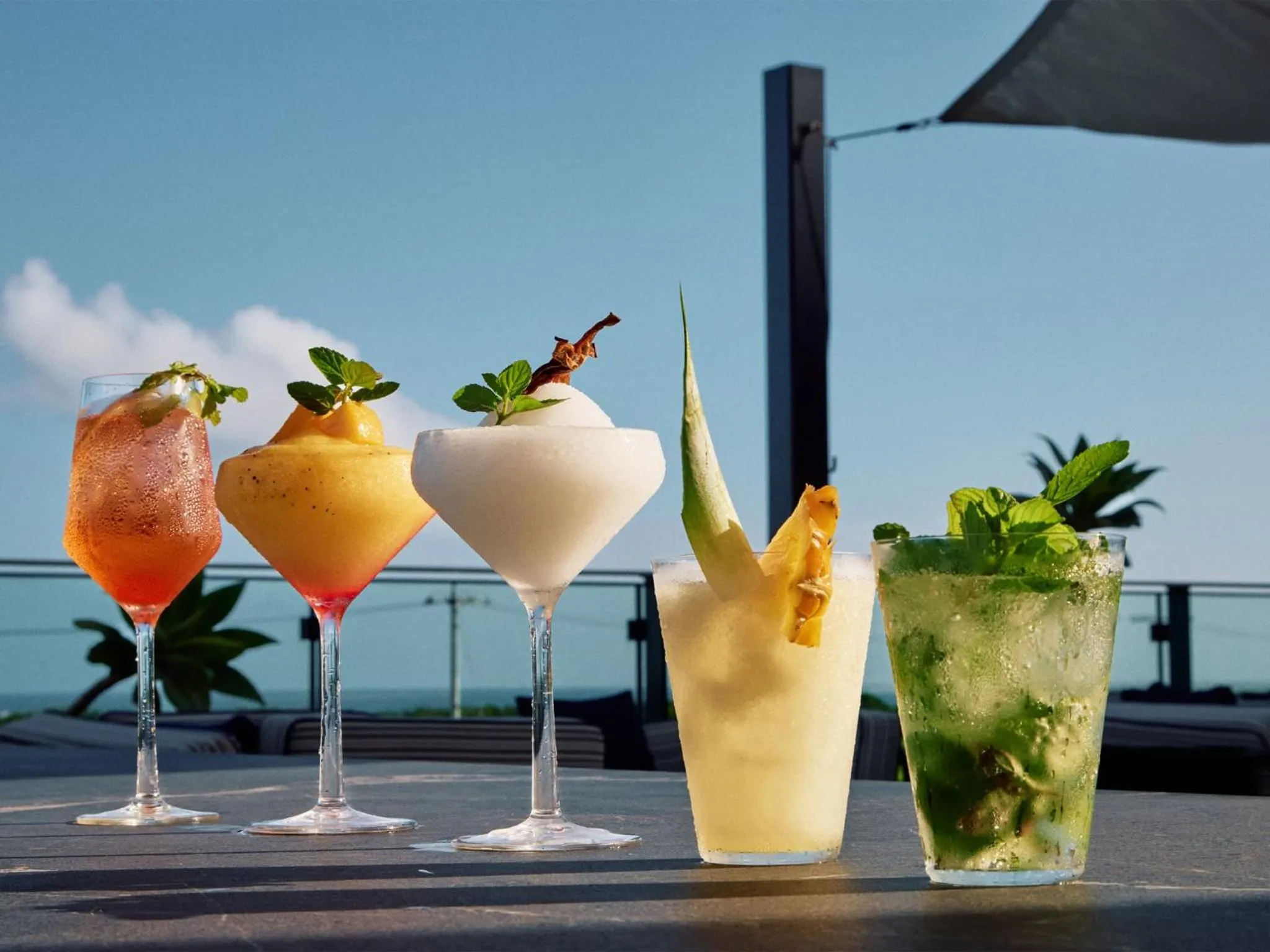Des cocktails colorés sont présentés sur une table en extérieur.