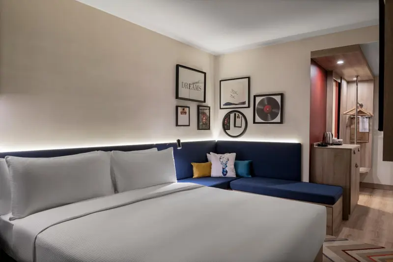 Une chambre lumineuse avec un grand lit et un coin salon intégré.