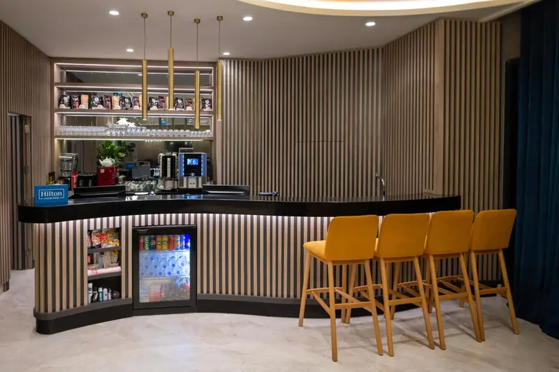 Un comptoir de bar moderne avec des tabourets et des bouteilles exposées.