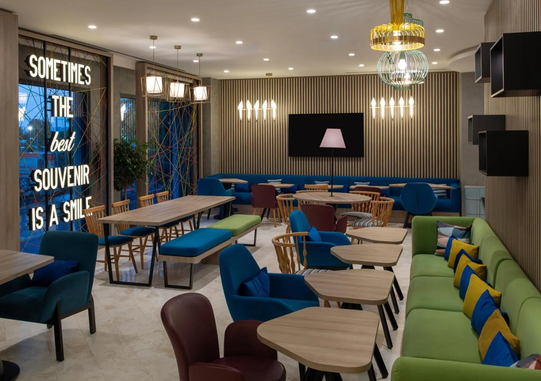 Une salle de restaurant avec des tables et des banquettes colorées.
