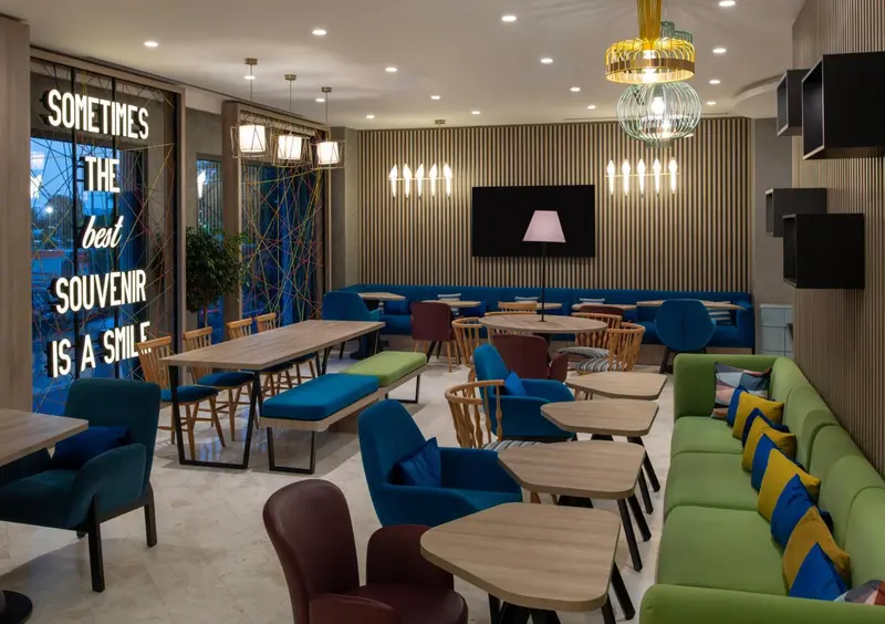 Une salle de restaurant avec des tables et des banquettes colorées.