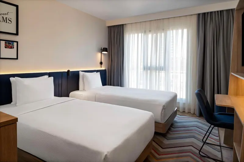 Une chambre avec deux lits simples et un bureau.