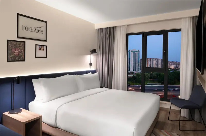 Une chambre d'hôtel lumineuse avec un grand lit et une vue sur la ville.