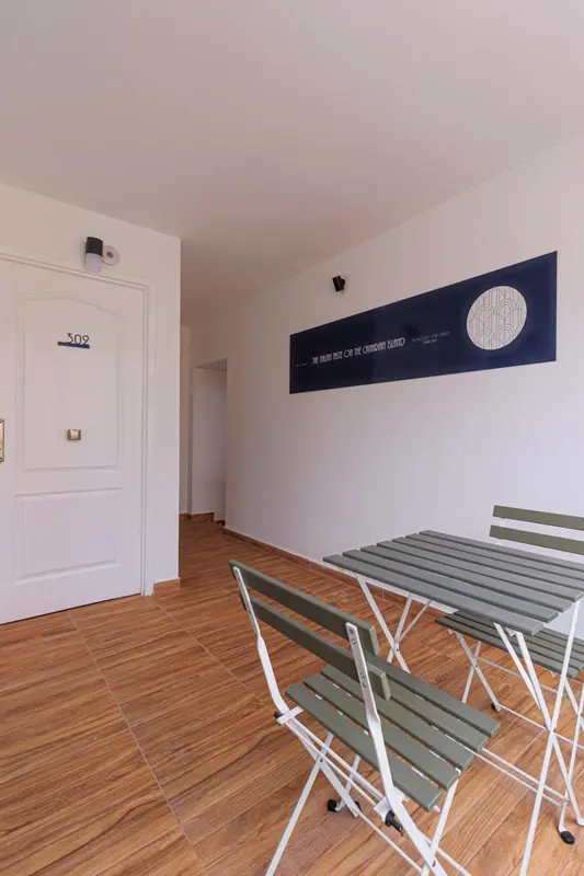 Une table et des chaises en bois se trouvent devant une porte et un mur blanc.