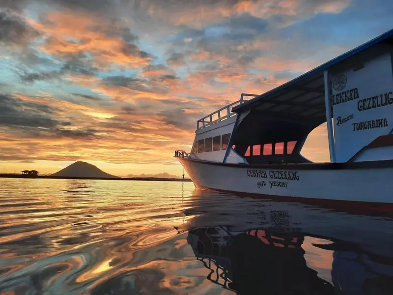Un bateau blanc navigue sur une mer calme au coucher du soleil.