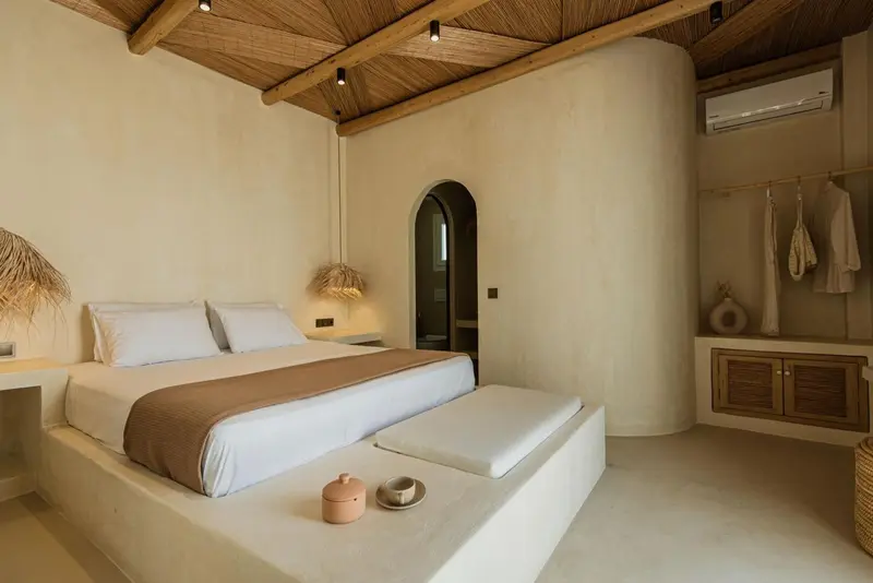 Une chambre lumineuse avec un grand lit et un espace ouvert sur un dressing.
