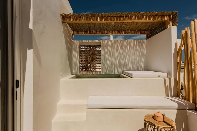 Espace de détente extérieur avec jacuzzi et mobilier blanc.