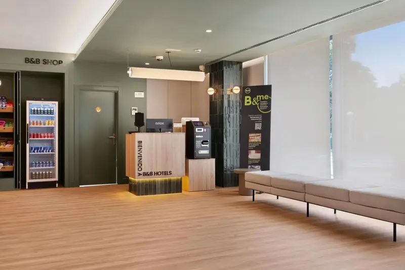 Hall d'accueil lumineux avec comptoir de réception et espace détente.