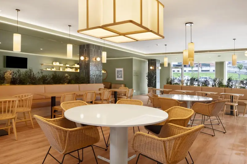 Une salle lumineuse avec des tables et des chaises en osier.