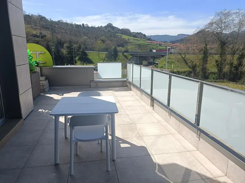Terrasse moderne avec table et chaises donnant sur un paysage vallonné.