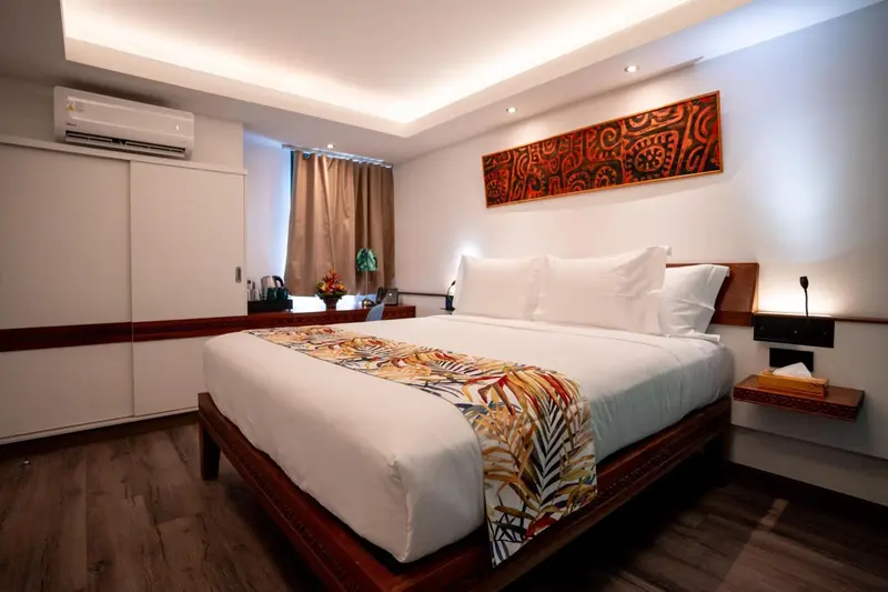Une chambre lumineuse avec un grand lit recouvert d'une courtepointe colorée.