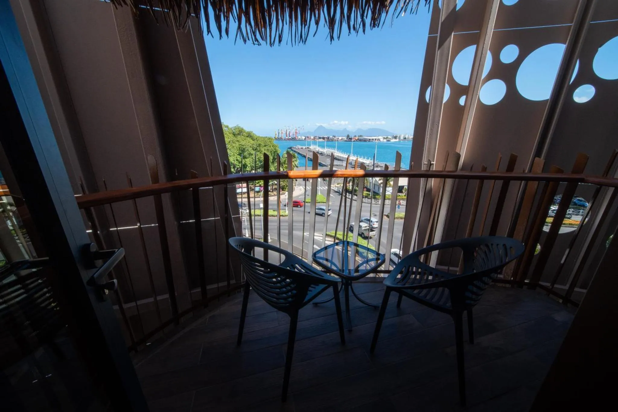 Deux fauteuils noirs sur un balcon avec vue sur la mer et la ville.