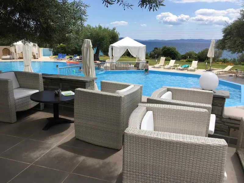 Espace de détente extérieur avec mobilier en osier près d'une piscine.